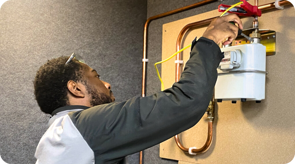 Man working on plumbing equipment in a training environment